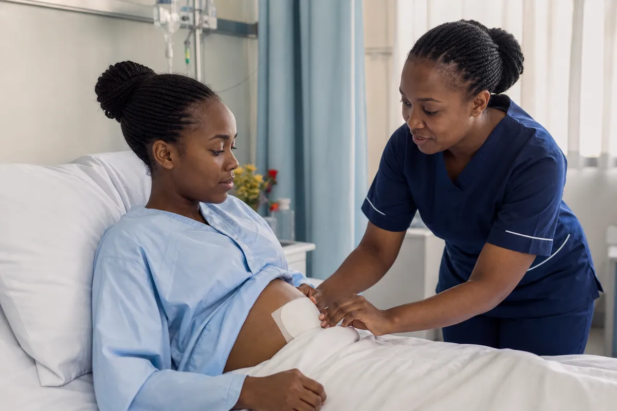 A nurse gently checks a young Kenyan woman's surgical dressing and provides aftercare guidance in a Nairobi clinic recovery suite.